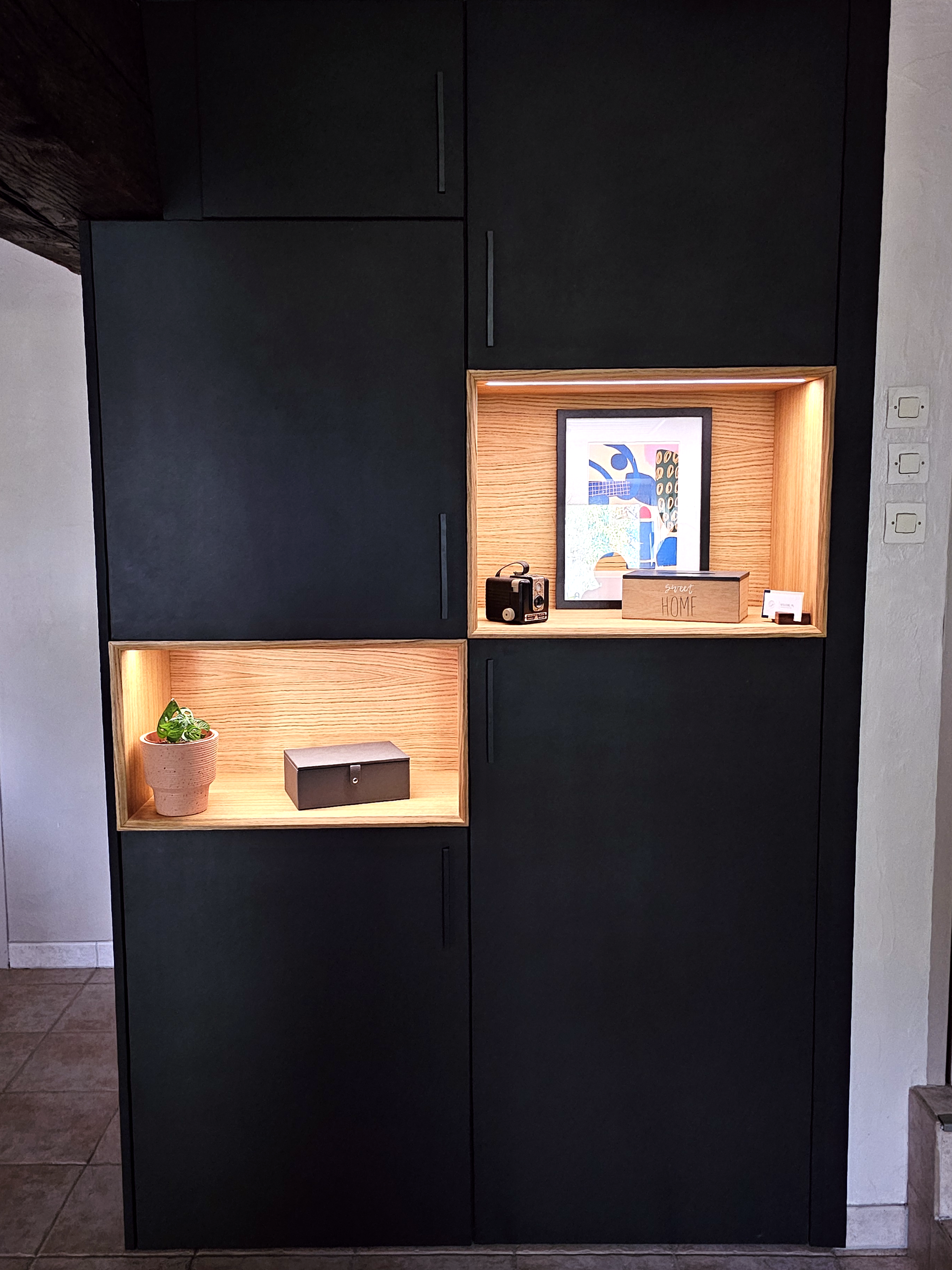 Détail d'un meuble d'agencement : niches en chêne éclairées dans un cadre noir mat