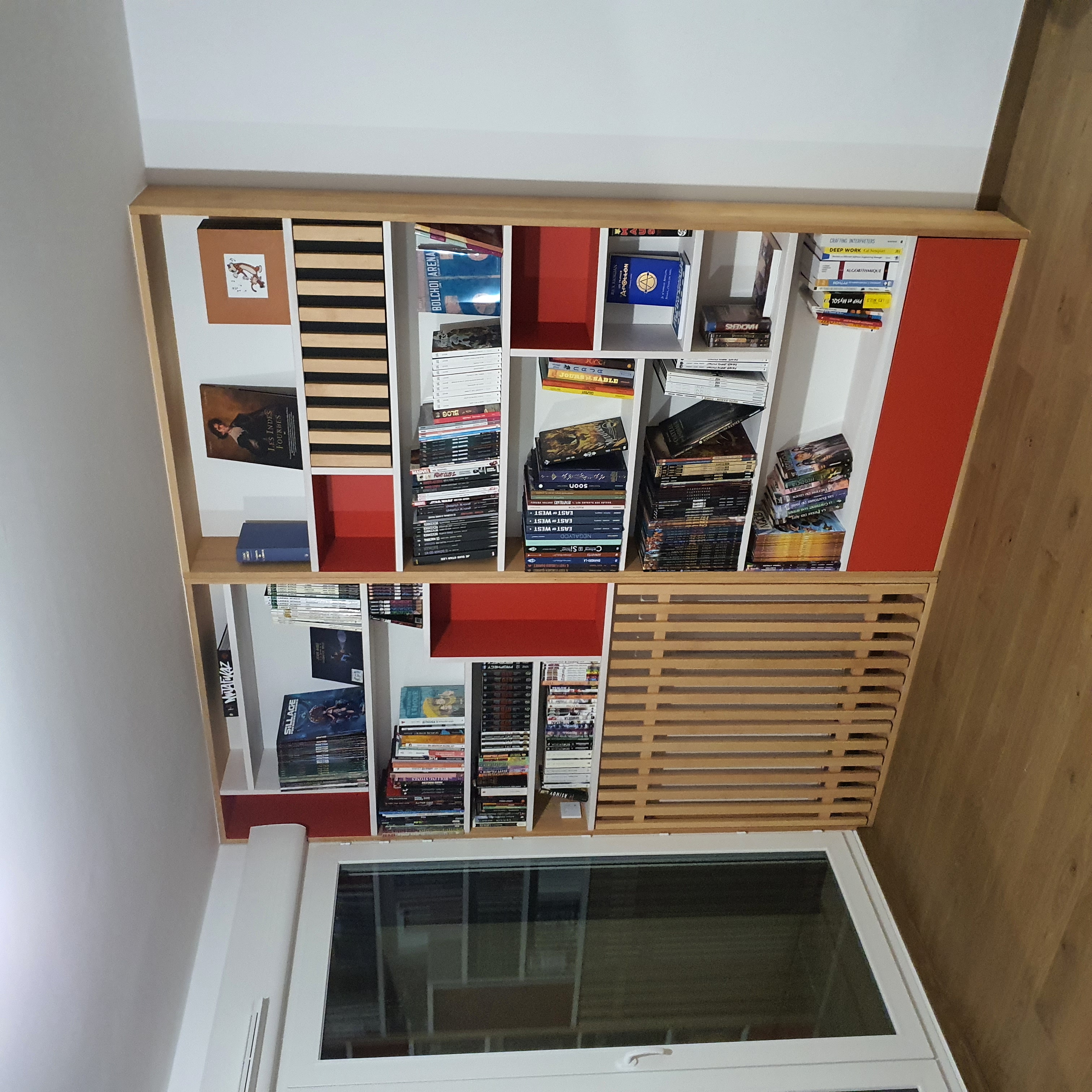 Bibliothèque sur-mesure en chêne avec niches rouges, claustra bois et rangements pour BD et livres