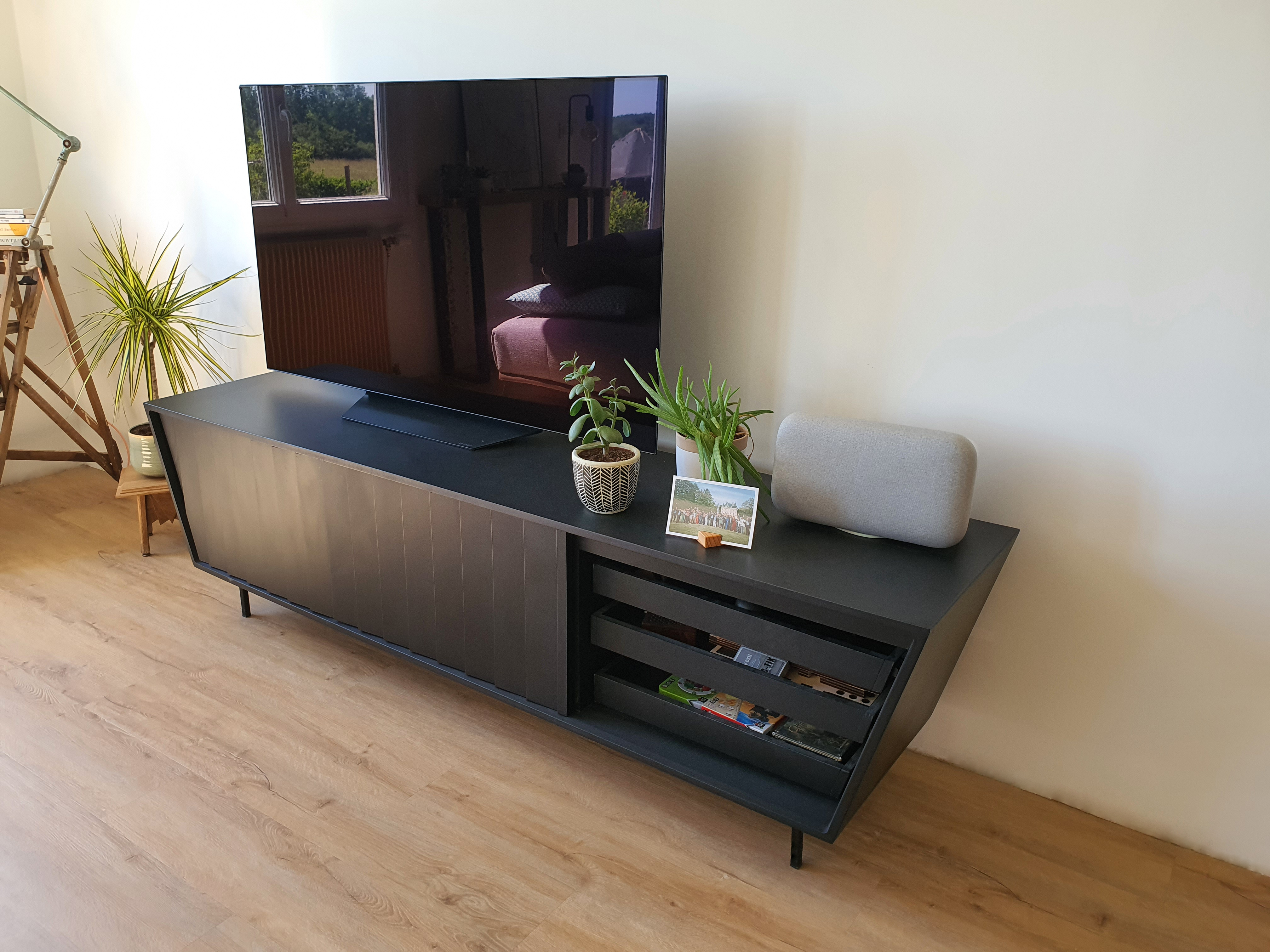 Meuble TV sur-mesure en valchromat noir mat avec porte coulissante en bois, étagères à lames et piètement acier