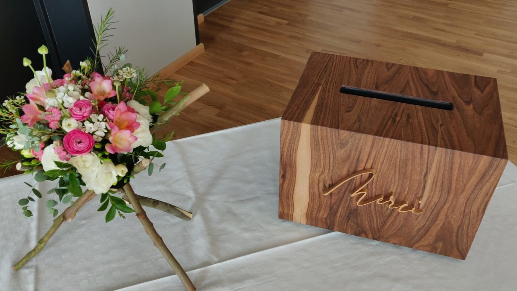 Urne de mariage en noyer avec inscription Merci dorée, à côté d'un bouquet de fleurs